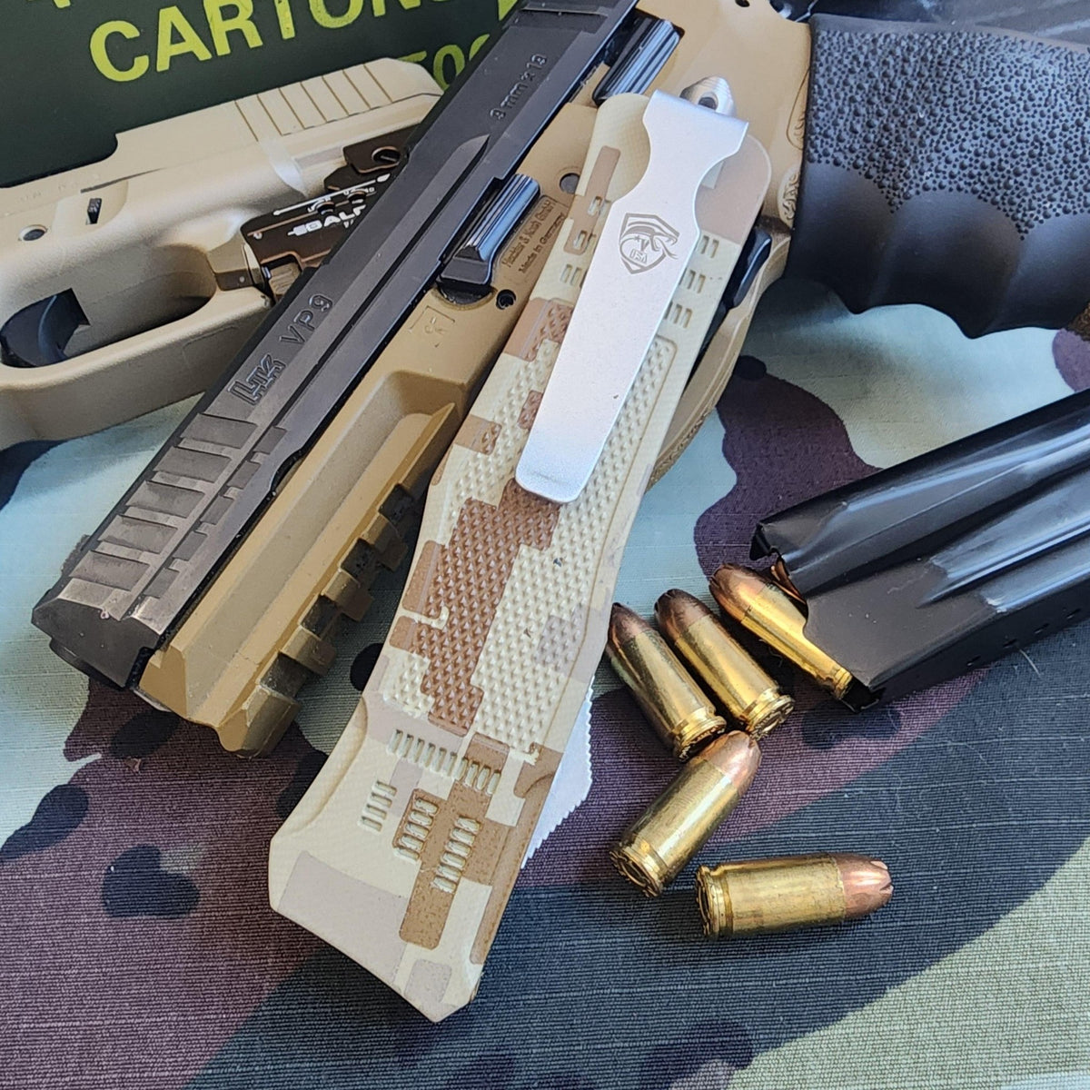 Handgun with camouflage grip and magazine, surrounded by bullets on a camouflage-patterned surface.