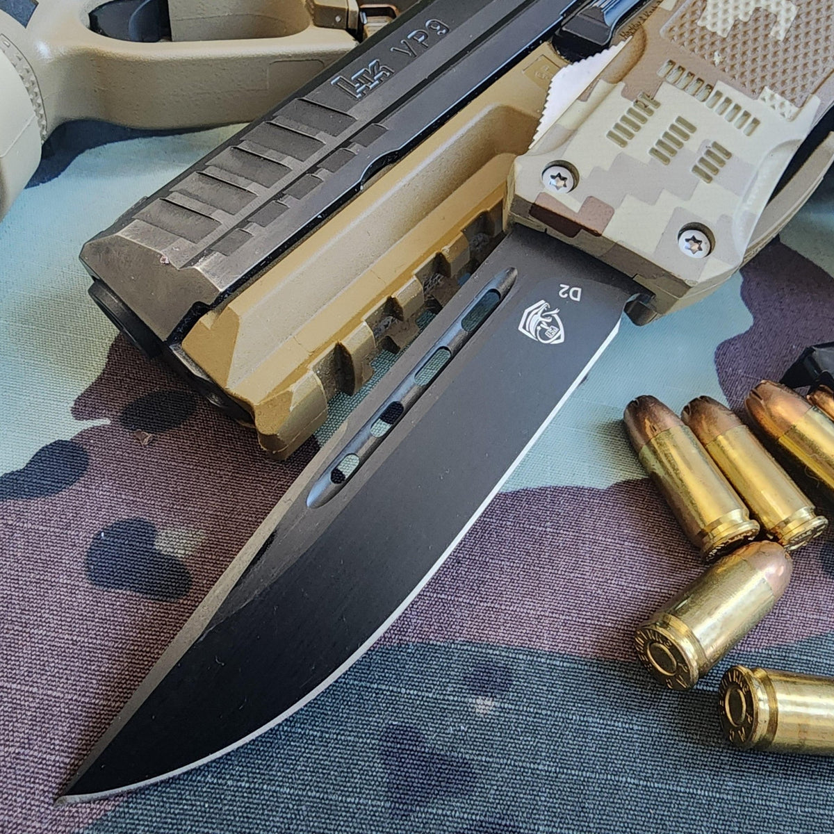 Folding knife with a tactical grip and bullets on a camouflage surface