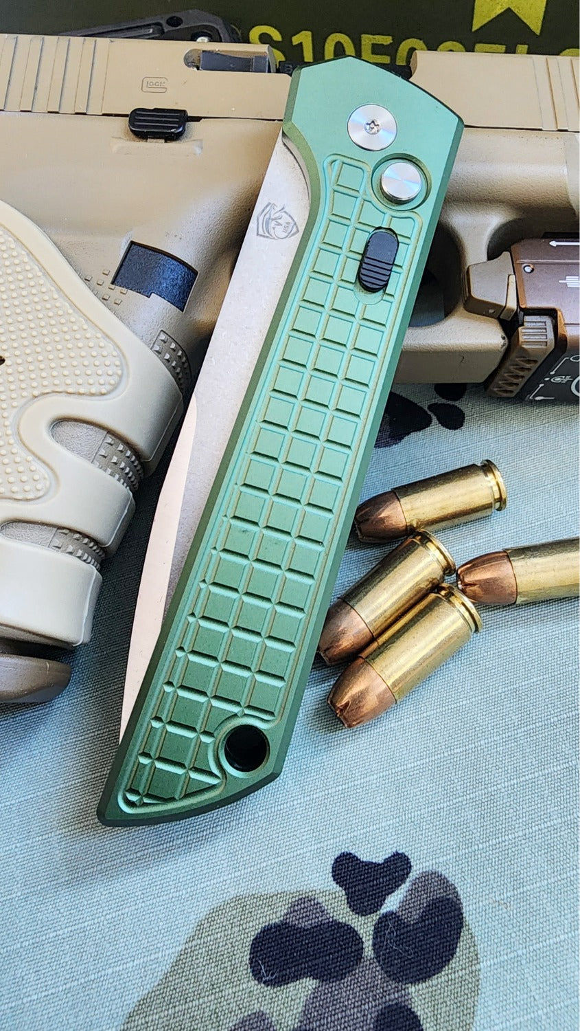 Green knife handle with bullets and a gun on a camouflage surface