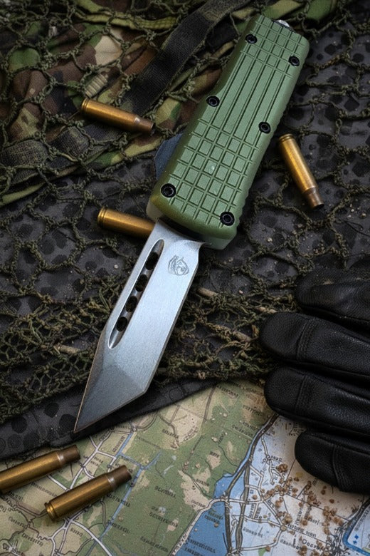 Green automatic knife on camouflage fabric with bullets and a map