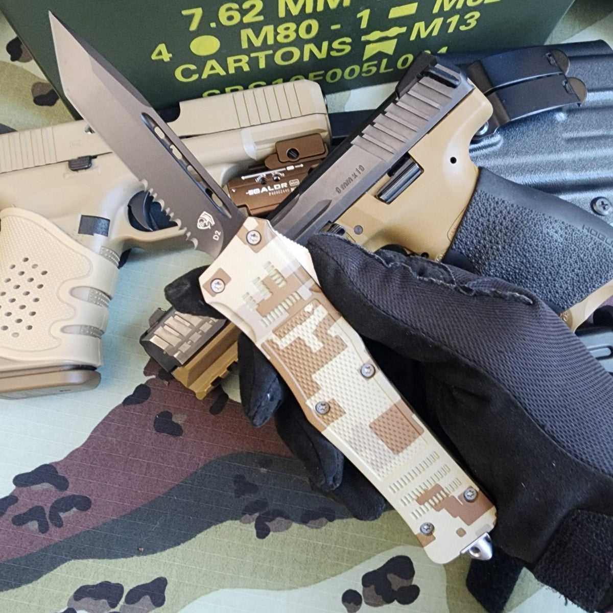 Knife with camouflage handle and tactical glove on a camouflage surface