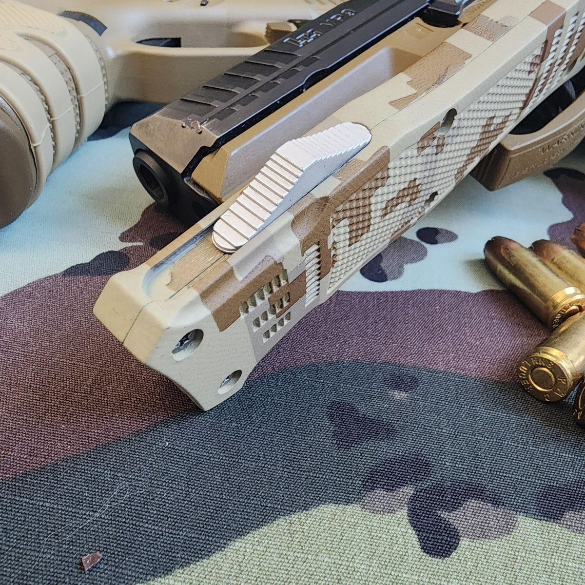 Camouflage-patterned gun and bullets on a camouflage fabric background
