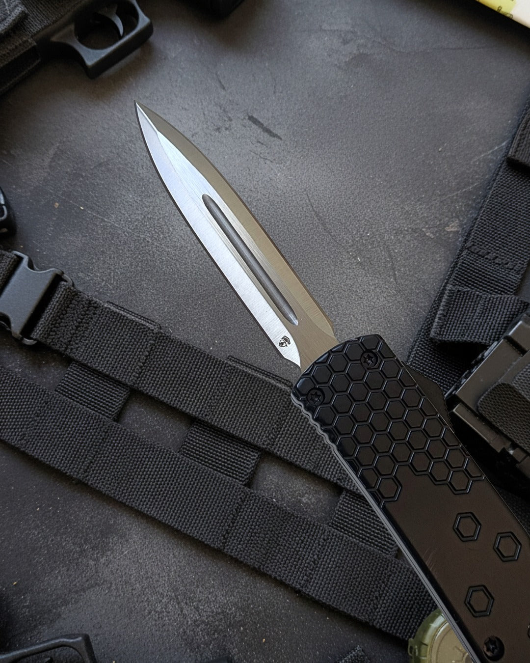 Tactical knife with black sheath on a textured surface