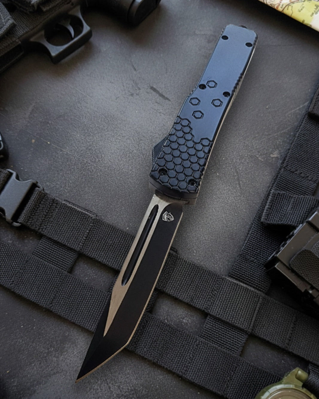Automatic OTF knife with black and gold design on a tactical background