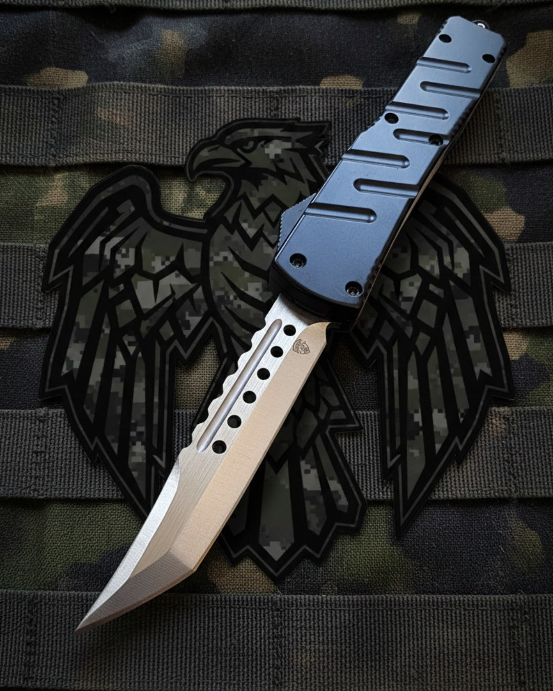 Automatic knife with a metallic blade and black handle on a camouflage background with an eagle emblem.