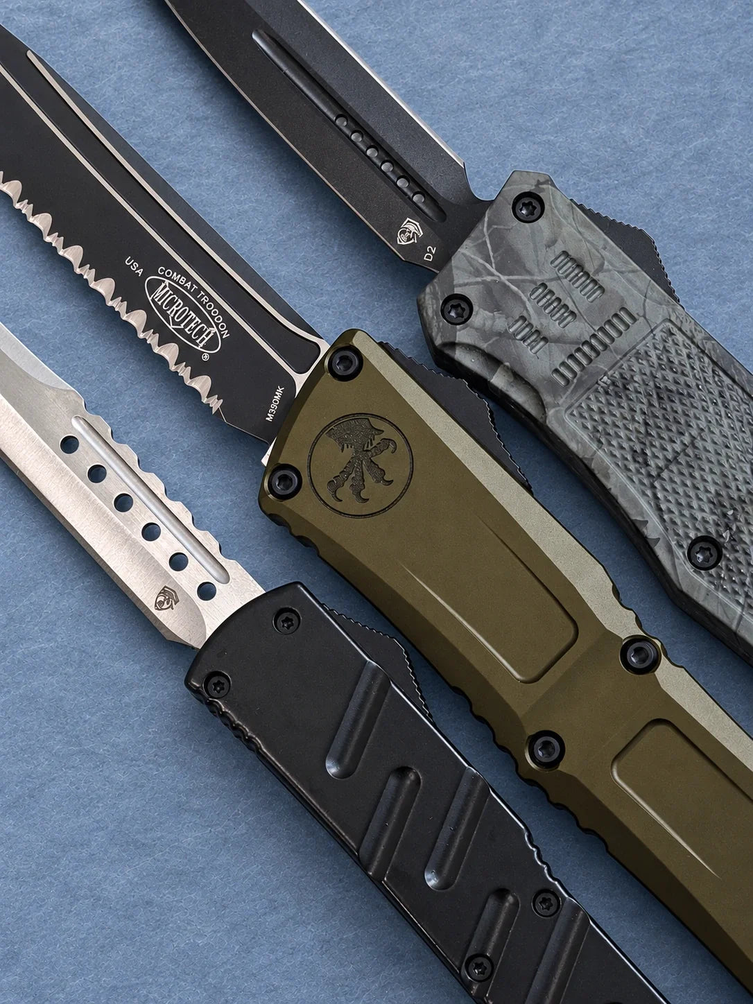 Double-action OTF (out-the-front) knives with black, olive and camouflage handles, featuring plain and serrated blades.
