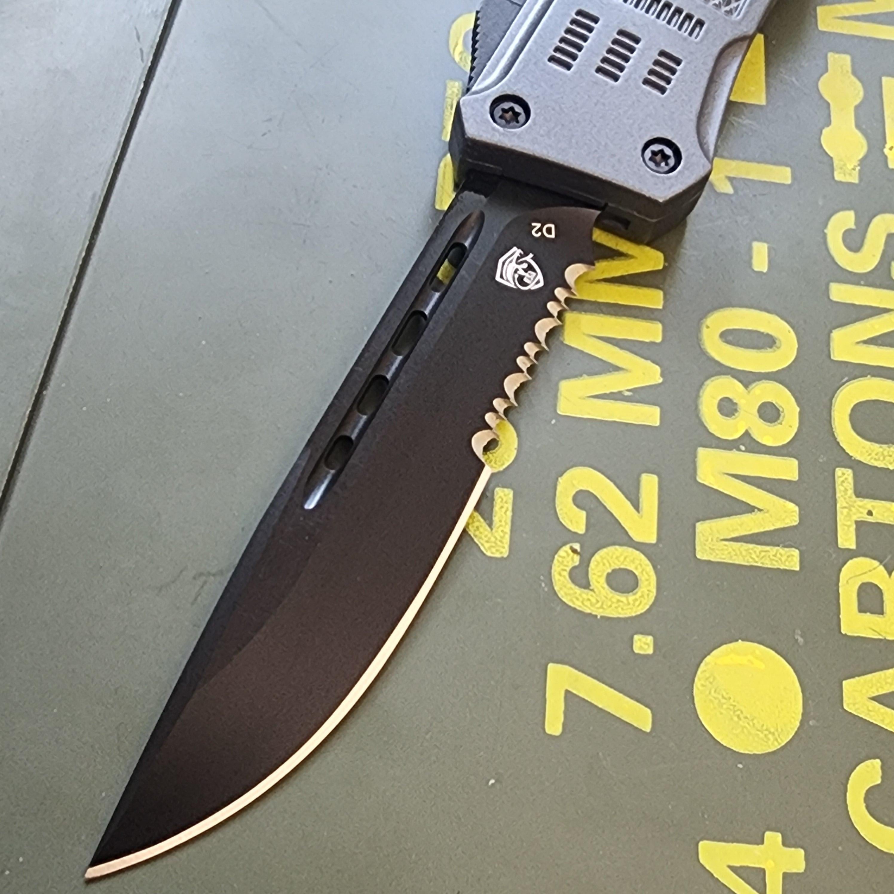 Folding knife with a black blade and silver handle on a green surface with yellow text.