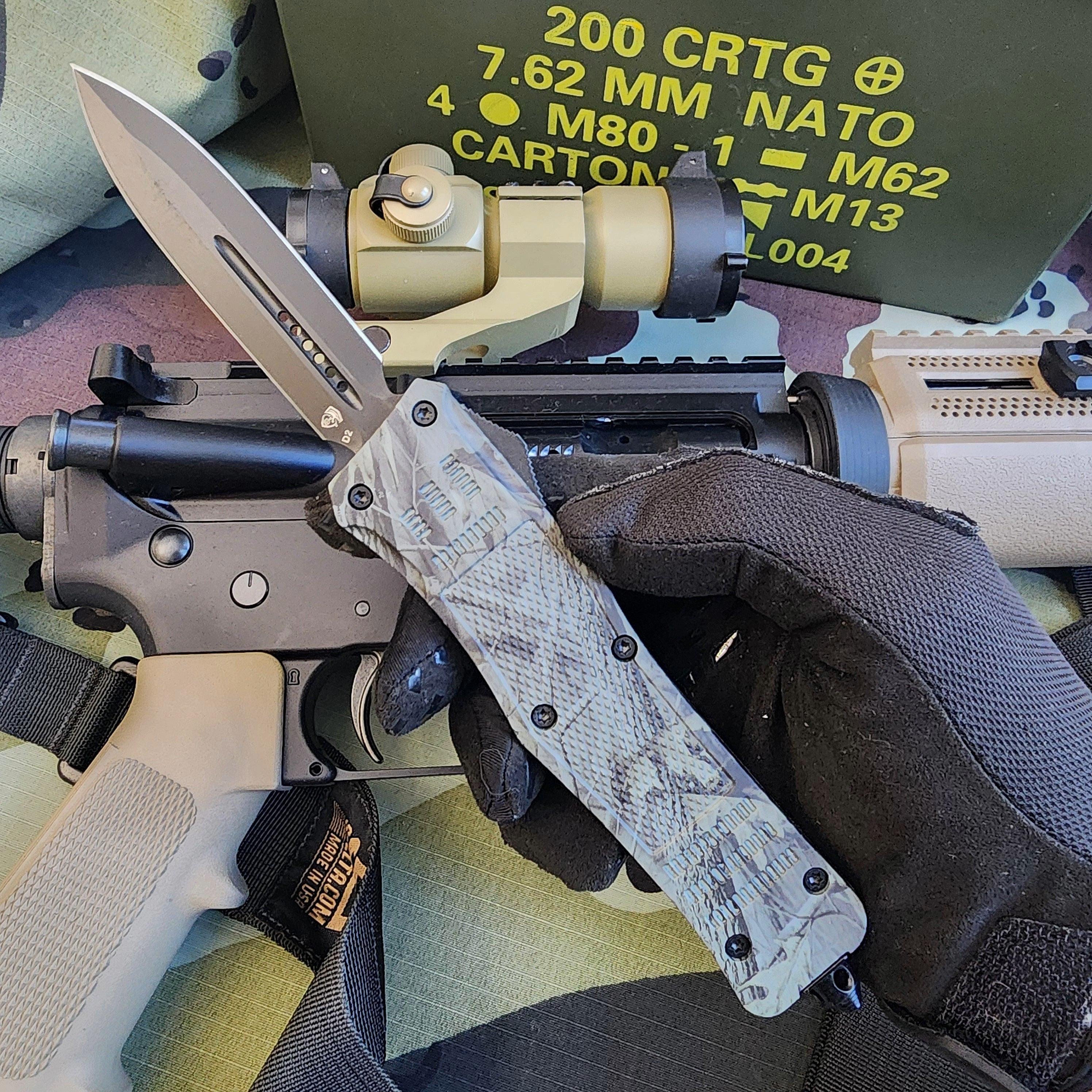 Hand holding a tactical knife with a rifle and green ammunition box in the background