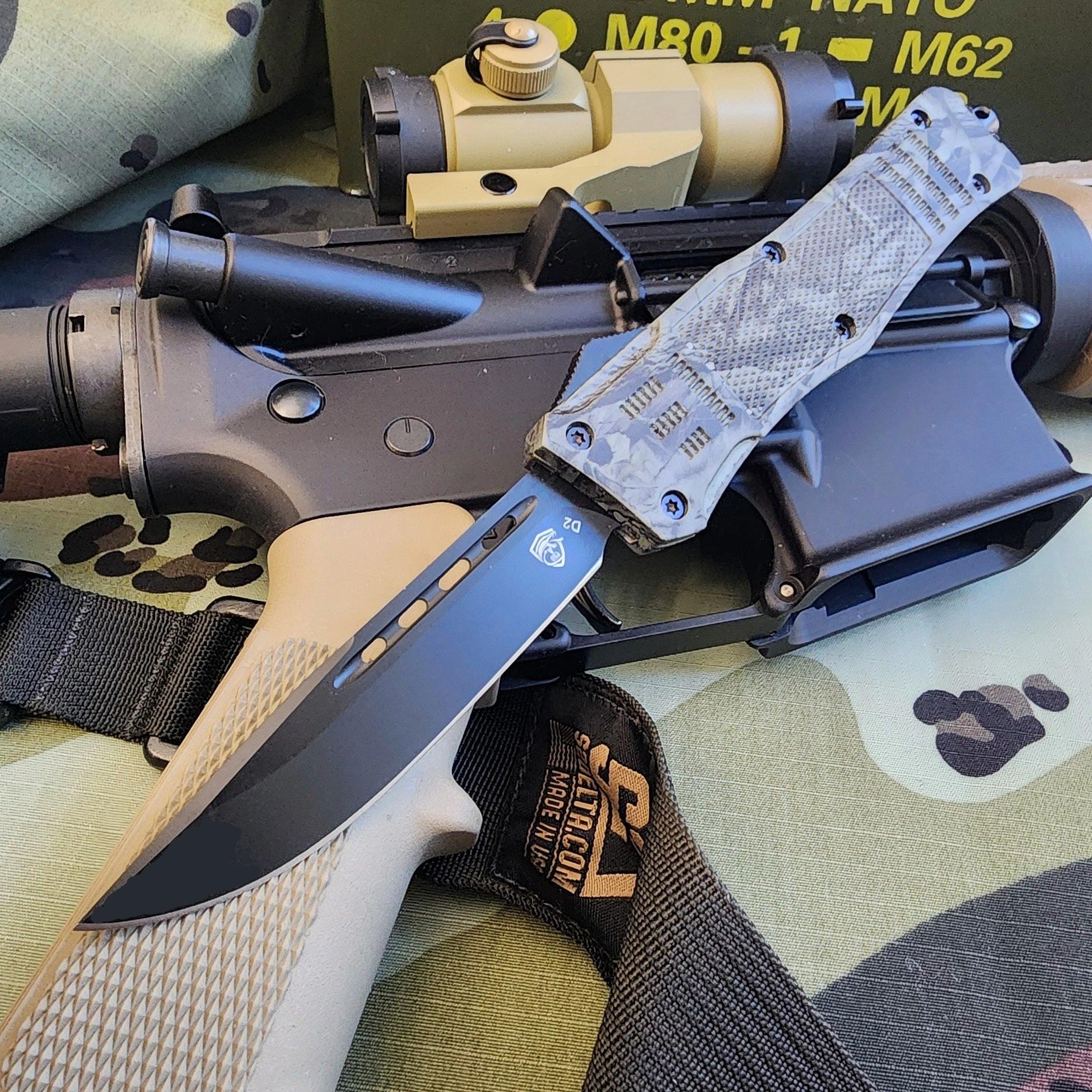 OTF knife with tactical rifle on a camouflage surface