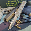 Out the Front automatic knife with camouflage pattern, gun, and ammunition on a camouflage surface