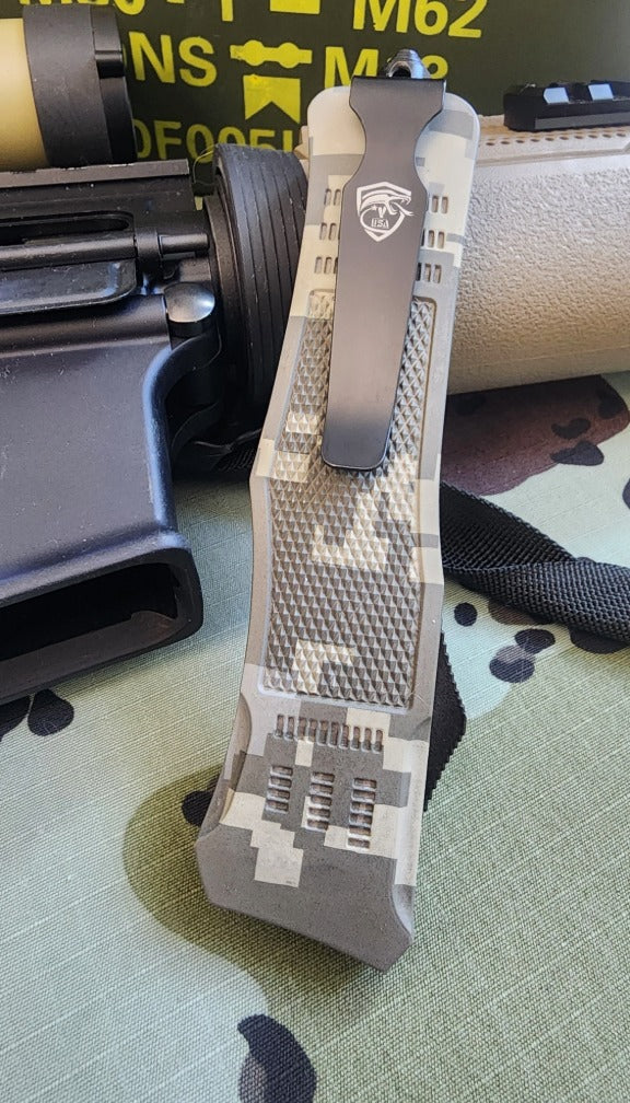 Camouflage-patterned tactical knife sheath on a textured surface with a blurred background