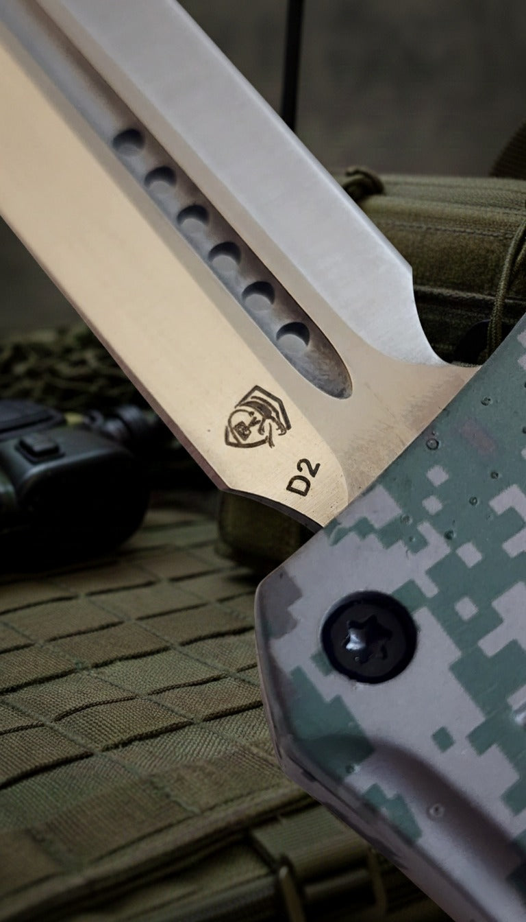 Close-up of a knife blade with a logo and 'D2' engraving on a camouflage surface.