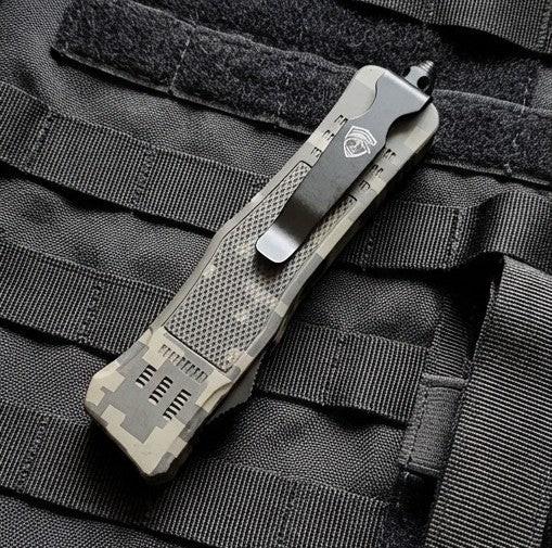 Tactical OTF knife with a camouflage pattern on a black tactical vest.