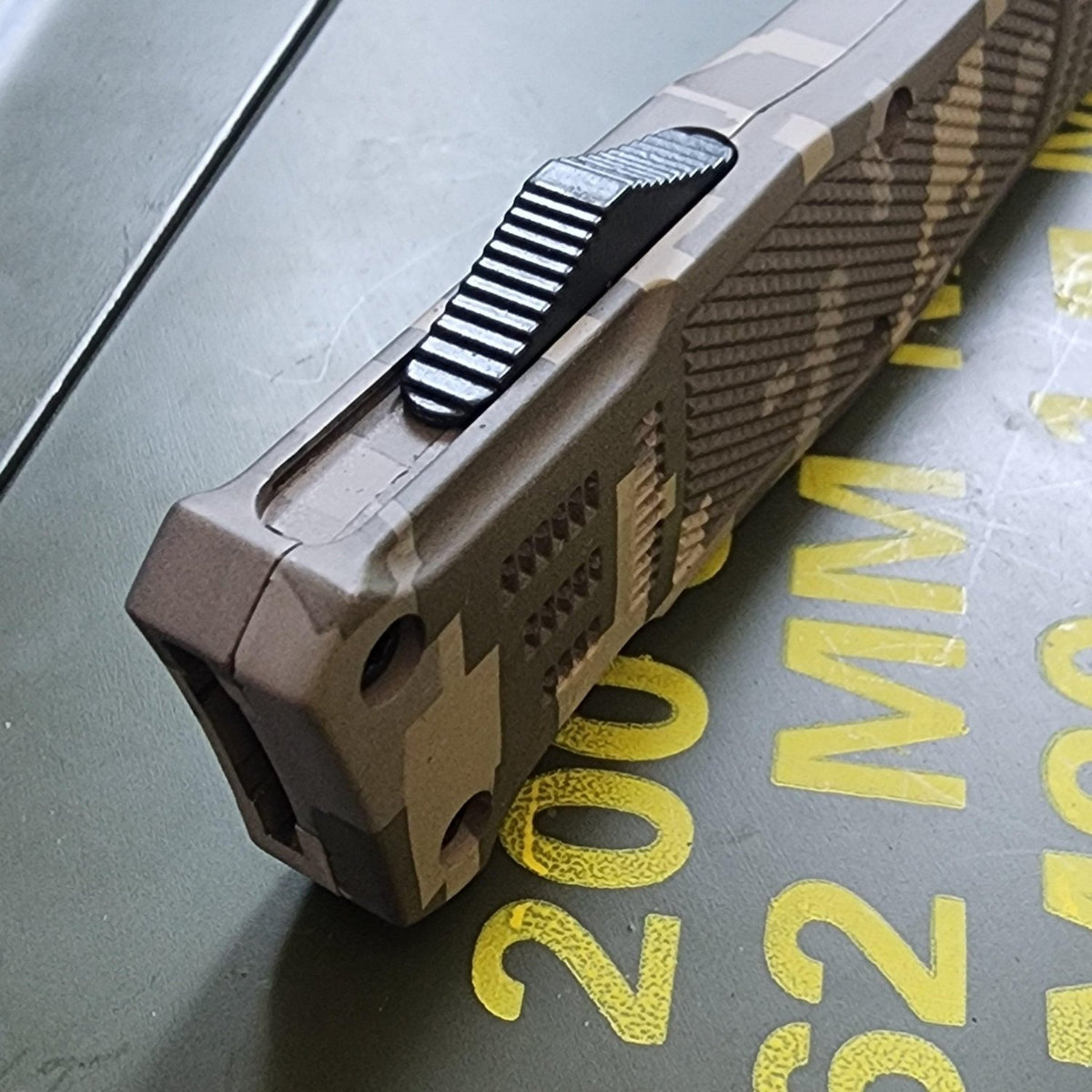 Close-up of a tactical knife with a textured handle on a metallic surface.