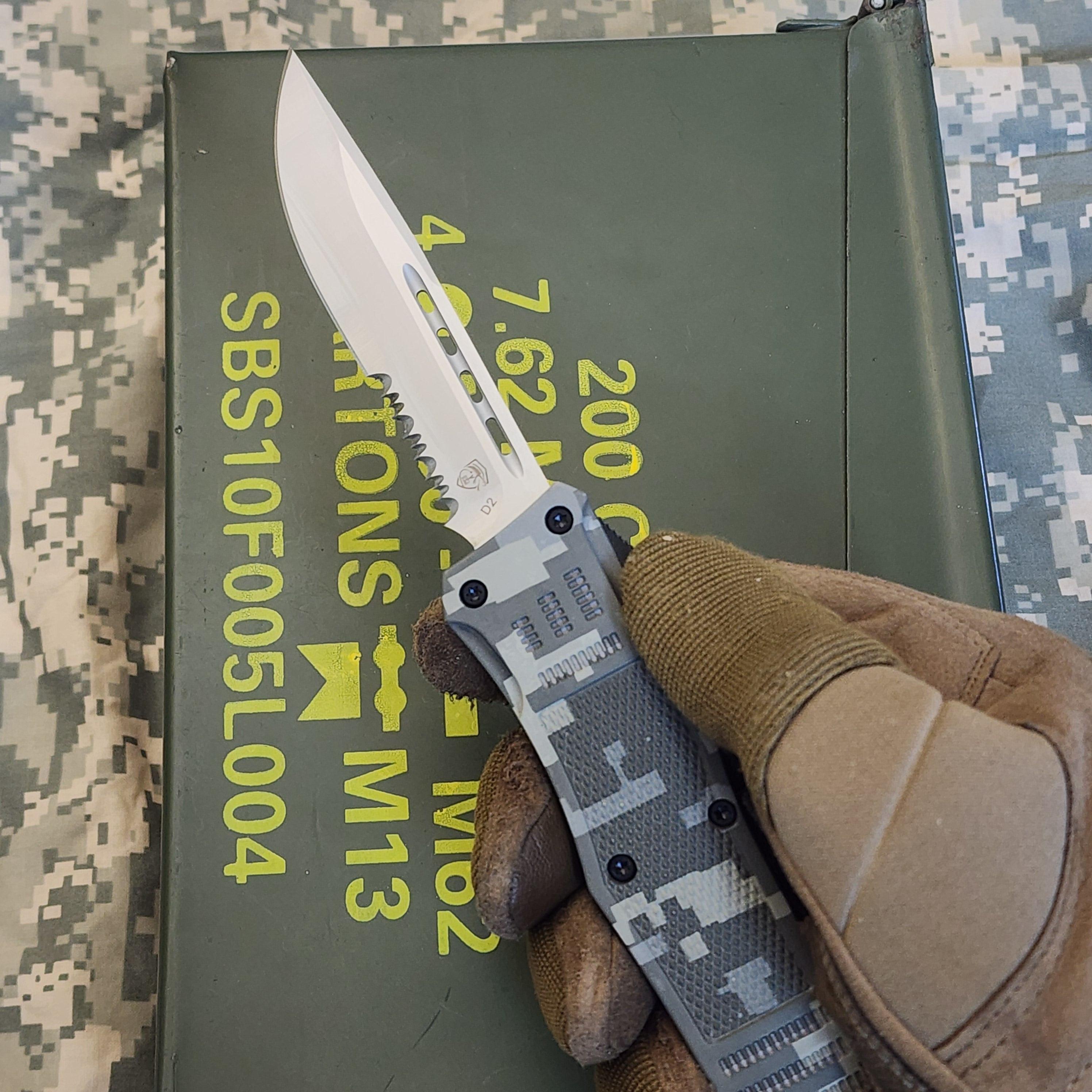 Hand holding a camouflage-patterned knife over a green ammunition box with military text.