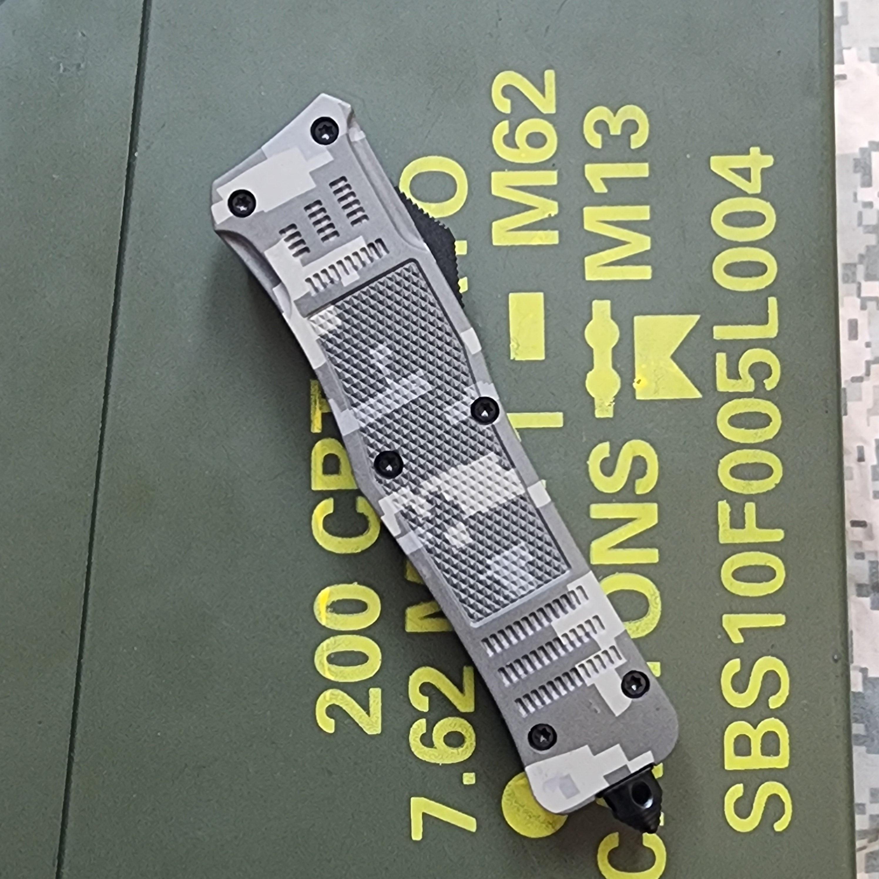 OTF knife with camo gandle on green ammp box
