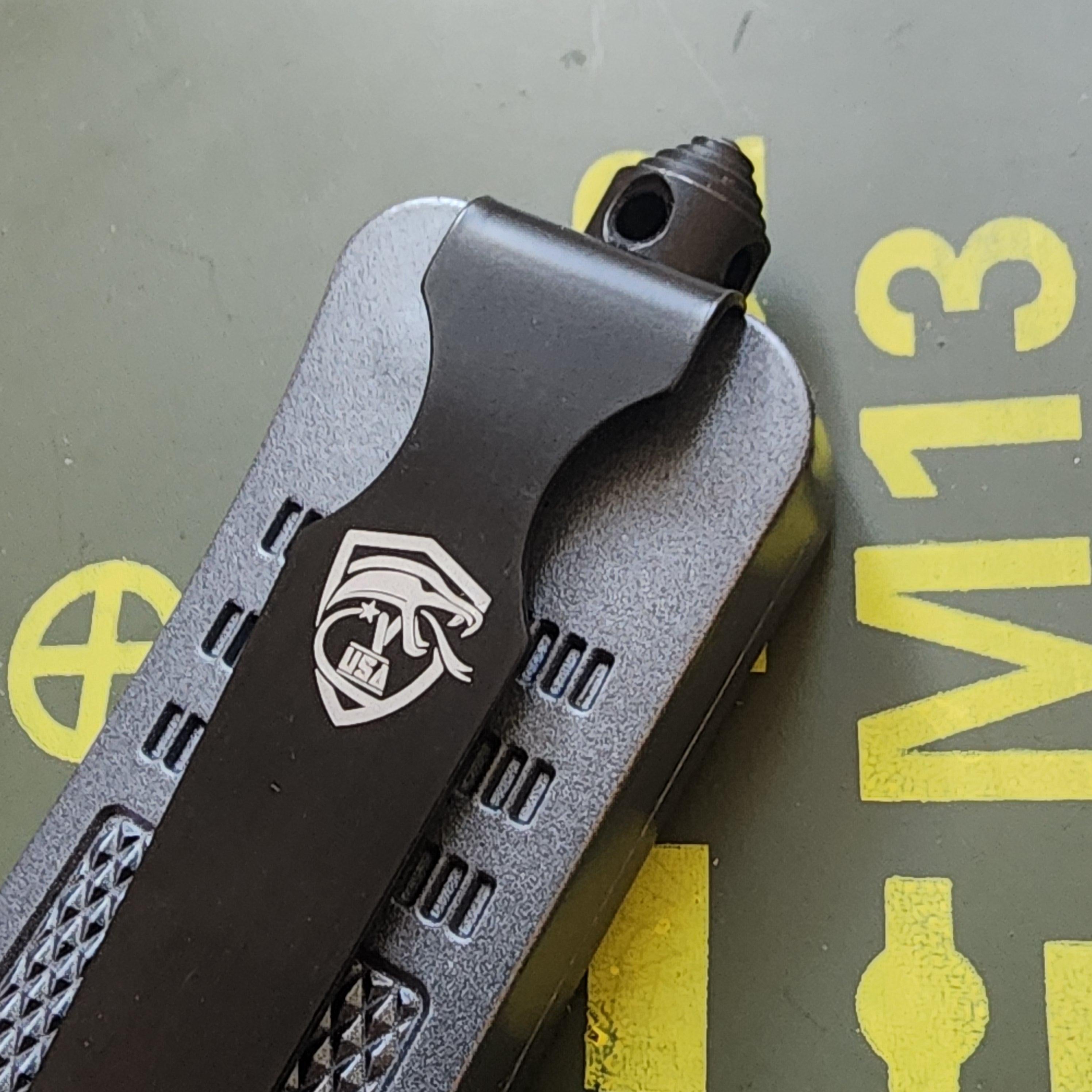 Black folding knife with a logo on a green background with yellow text