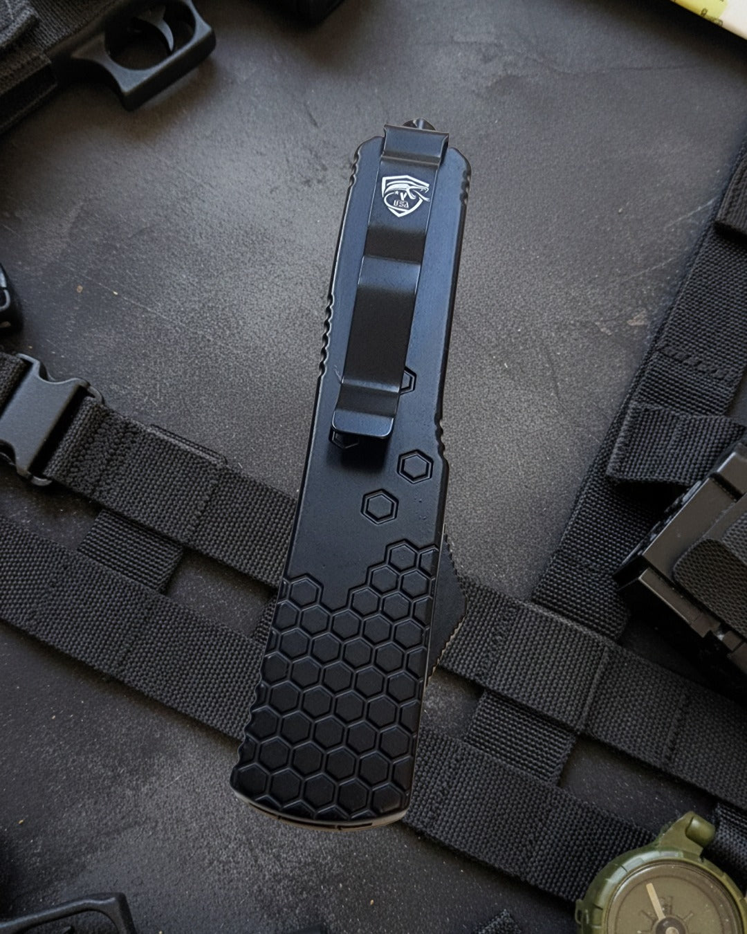 Black tactical knife with a hexagonal pattern on a dark background